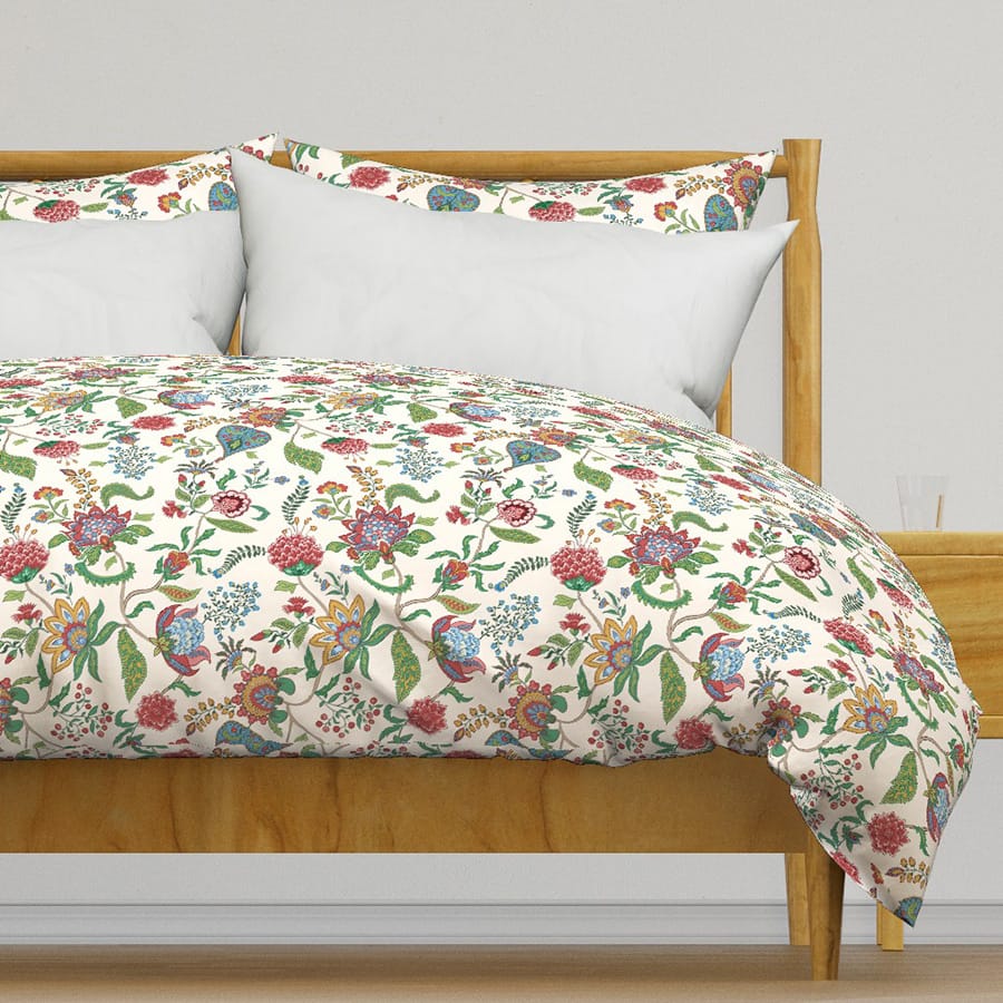 Large scale traditional Indian floral chintz wallpaper and fabric in red, green, blue, gold on pinkish beige, here on Duvet Cover designed by Gabrielle Marlow