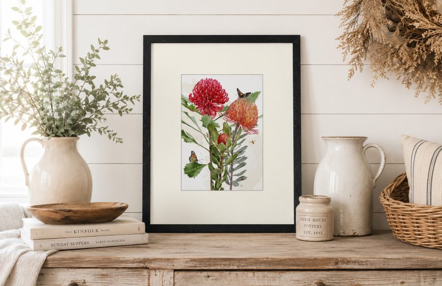 Red protea and waratah botanical illustration framed print with butterflies, styled on a rustic sideboard