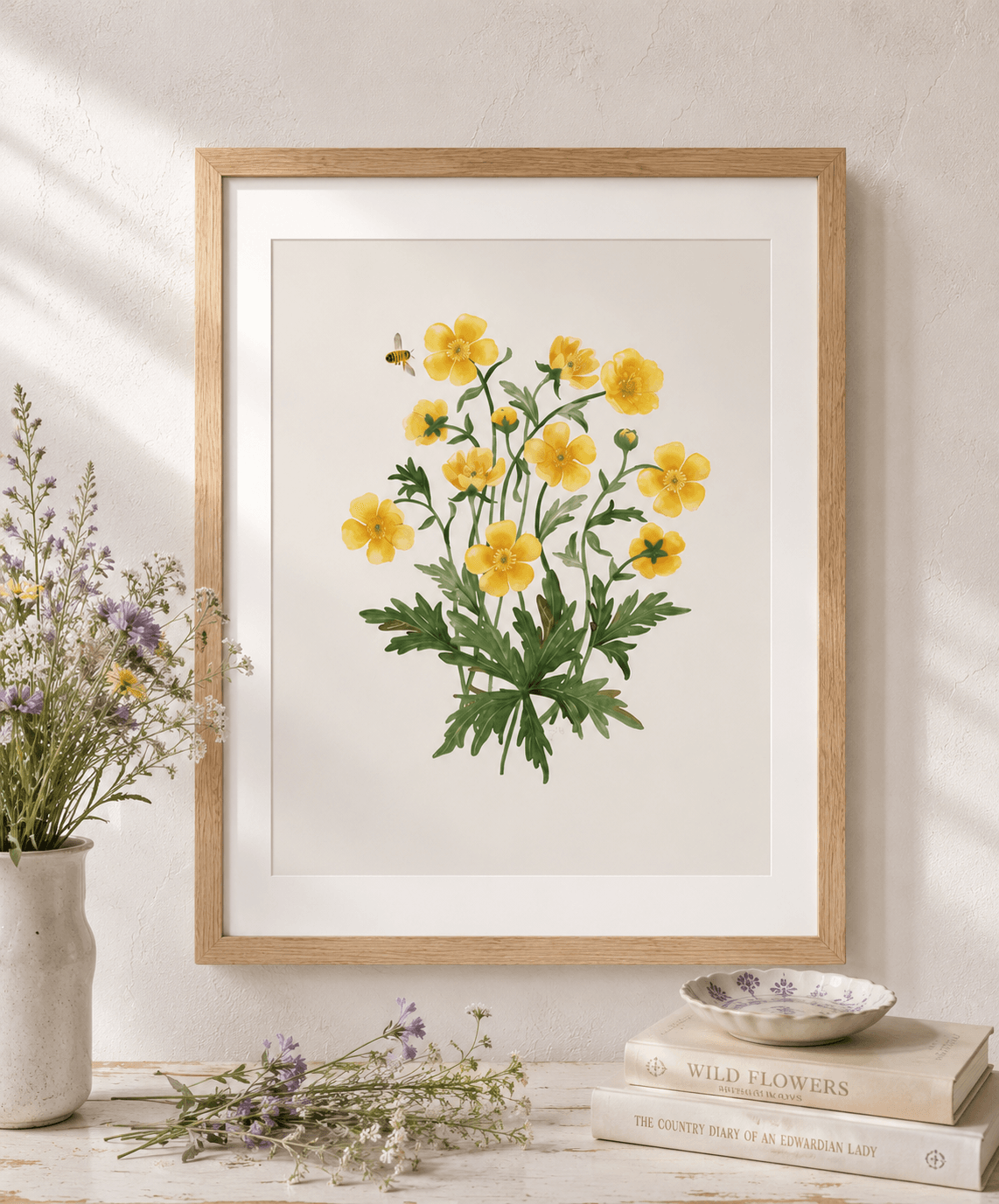 Framed yellow buttercup watercolour botanical art print with bee, above a rustic console table