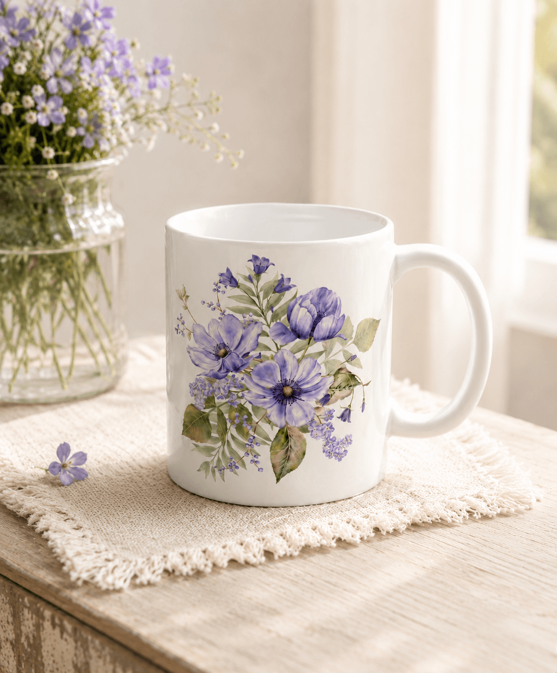 White mug with a hand-painted purple floral bouquet, styled with a small purple flower on a linen cloth