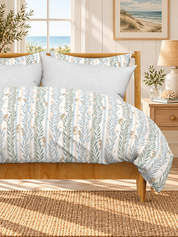 Bedroom with a wooden bed dressed in a duvet cover with vertical seaweed stripes in soft sage, blue and sand, dotted with small seahorses and starfish, with an ocean view through the window